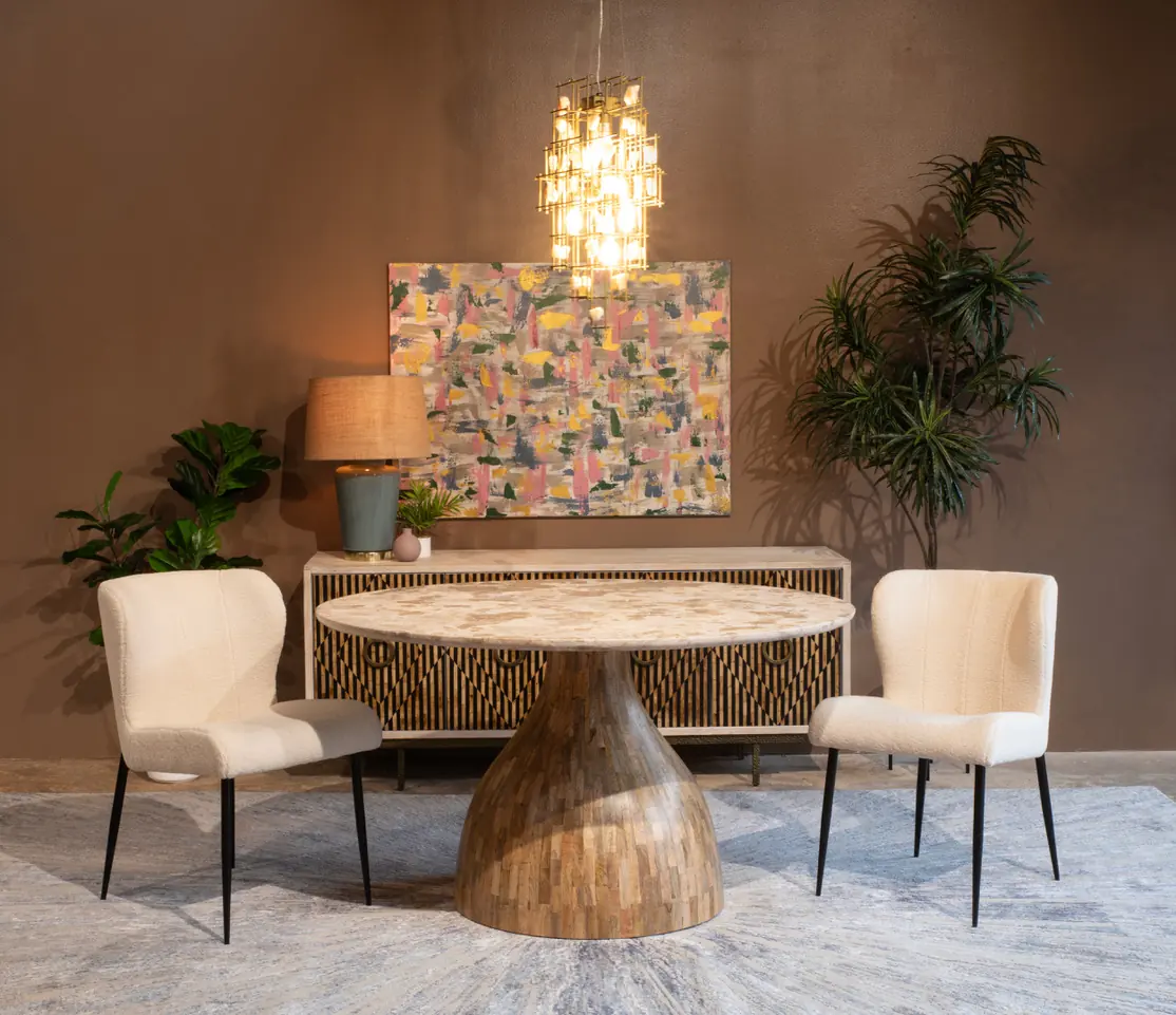 A dining room with an abstract painting above a sideboard and a marble table