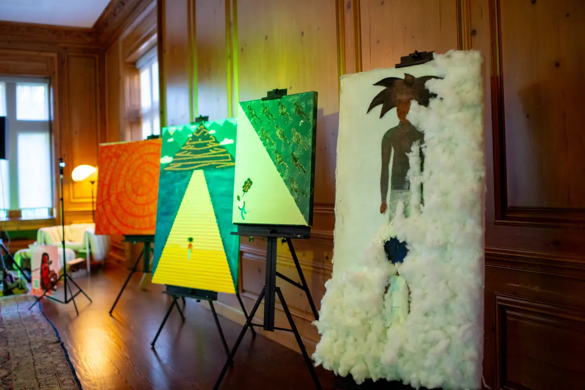 Paintings by Micah The Artyst displayed on easels in a wood-paneled room
